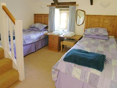 a bedroom with two beds and a desk and a mirror at Buzzard Barn in Saint Martins Green