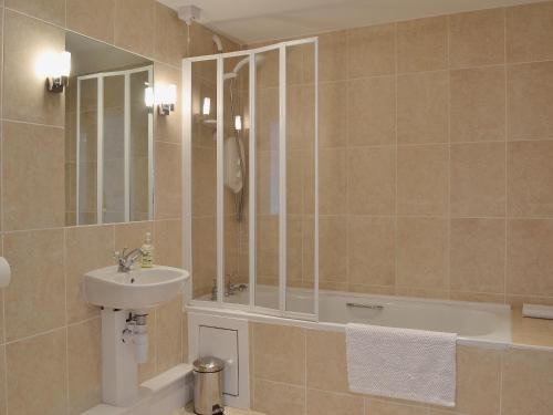 uma casa de banho com um lavatório, uma banheira e um espelho. em Y Stabl em Llanwrda