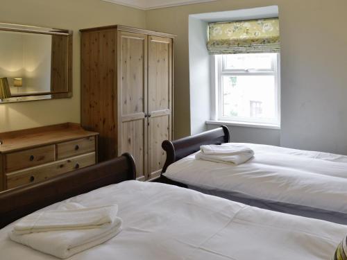 a bedroom with two beds and a dresser and a mirror at Craven House in West Burton