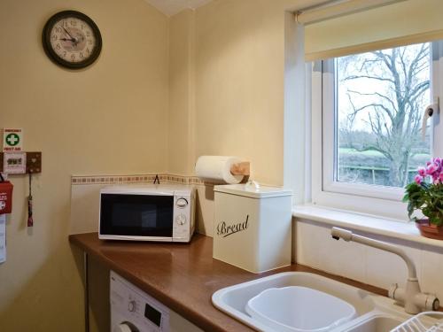 a bathroom with a microwave and a sink and a window at Sparrows Nest in Sampford Arundel