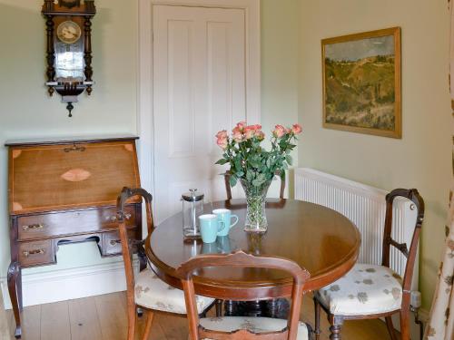 a dining room table with a vase of flowers on it at Garden Cottage in Westleigh