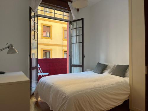 een slaapkamer met een bed en een groot raam bij Bonito apartamento muy céntrico in Bilbao