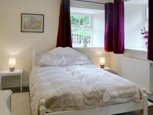a white bed in a bedroom with two windows at The Cottage in Blackwood