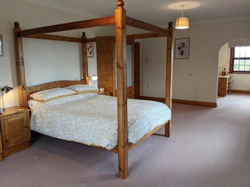 a bedroom with a wooden canopy bed in a room at Brambleside in Mawbray