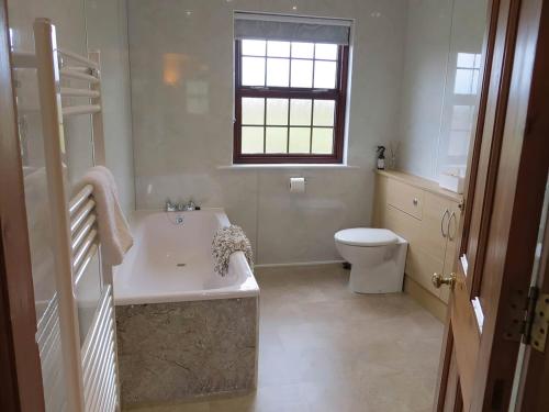 a white bathroom with a tub and a toilet at Brambleside in Mawbray