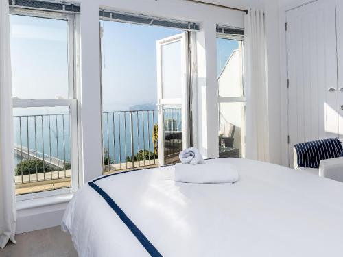 a white bed with a stuffed animal on it in a room with windows at Marina Beach House, Torquay in Torquay