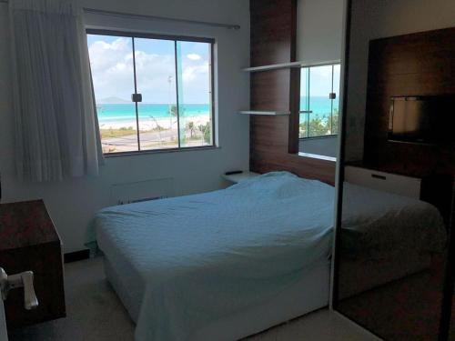 a bedroom with a bed and a view of the beach at FORTE DA PRAIA in Cabo Frio