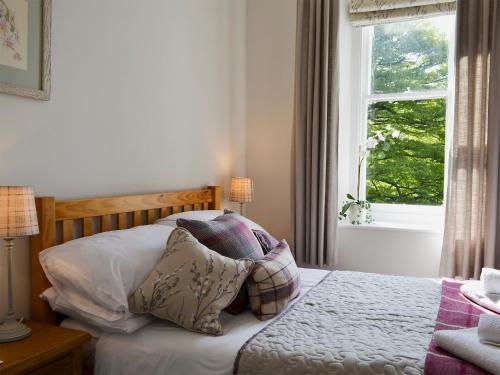 a bedroom with a bed with pillows and a window at 4 The Old Vicarage in Far Sawrey