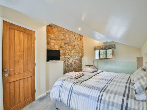 a bedroom with a bed and a stone wall at Horseshoe Cottage in Bolton by Bowland