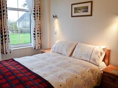 a bed in a bedroom with a large window at Gladstone Cottage in Castletown