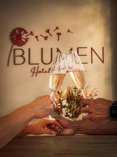 two people holding up glasses of champagne in front of a sign at Blumen Hotel Boutique in Canela
