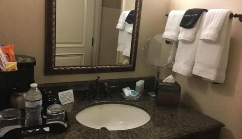 een badkamer met een wastafel, een spiegel en handdoeken bij Liberty Hotel, Ascend Hotel Collection in Cleburne