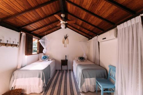 a room with two beds and a ceiling fan at Vila Luz in Caraíva
