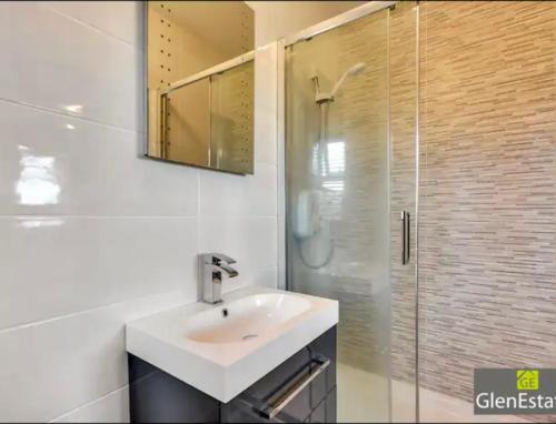 y baño blanco con lavabo y ducha. en Bridgeview en Carrigart