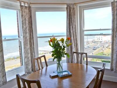 a dining room table with a vase of flowers on it at Sky Lark in Cromer
