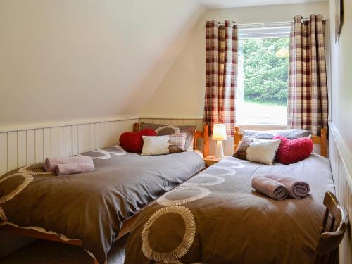 two twin beds in a room with a window at Glenlivet View in Auchnastank