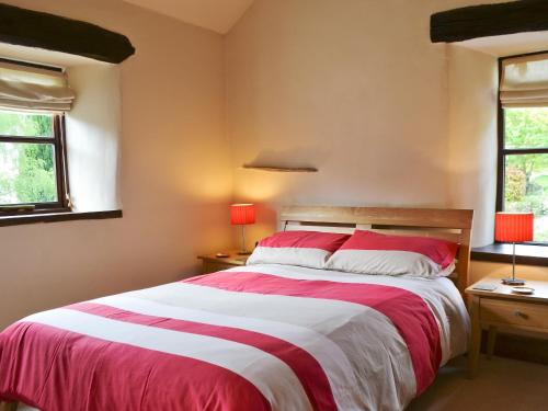 a bedroom with a red and white bed and two windows at Beck Edge in Braithwaite