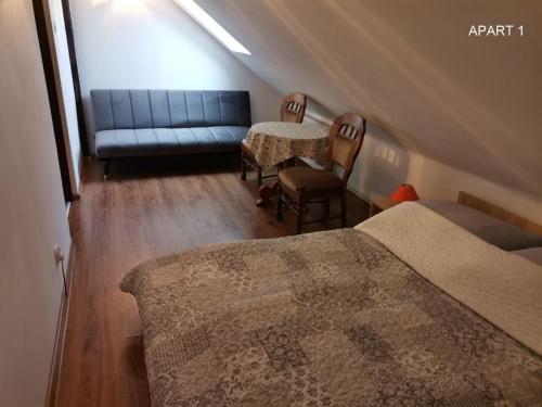 a attic bedroom with a couch and a table and chairs at Apartament Wolin nad wodą koło Miedzyzdrojów in Wolin