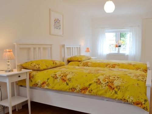 1 dormitorio con 2 camas y edredón amarillo en Llifon en Llanwnda