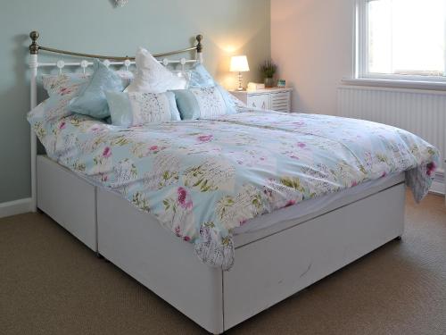 a bedroom with a white bed with a floral bedspread at Pams Plaice in Offord Cluny