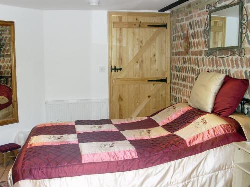a bedroom with a bed and a brick wall at High House Holiday Cottages 1 in Hooe