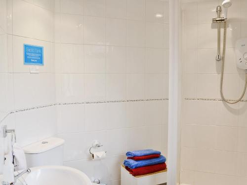 a white bathroom with a shower and a sink at High House Holiday Cottages 1 in Hooe