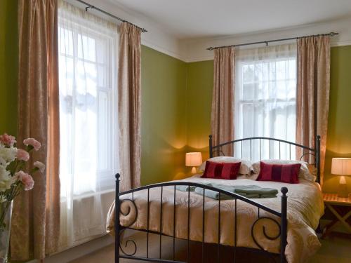 a bedroom with green walls and a bed with red pillows at Caberfeidh in Grantown on Spey