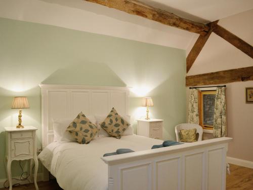a bedroom with a white bed with two tables and two lamps at Barley House - RFFN in Fownhope