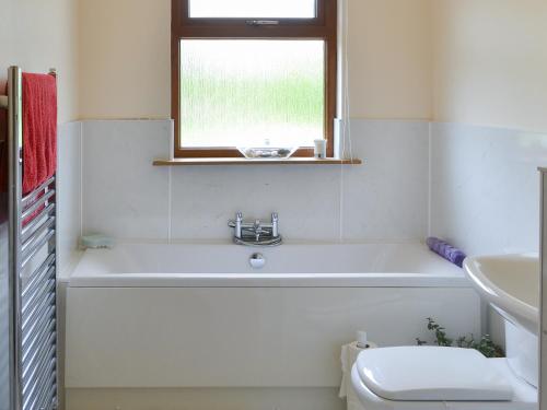 a bathroom with a tub and a sink and a window at Riverside in Annan