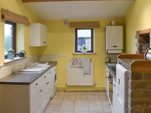 a kitchen with yellow walls and white cabinets at Ladycroft Barn in Bamford