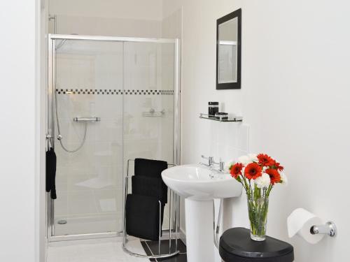 a white bathroom with a sink and a shower at Rose Cottage - 28176 in Fairgirth