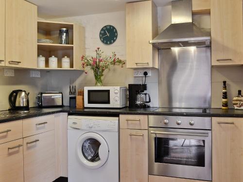 a kitchen with a washing machine and a microwave at The Stables in Woolaston