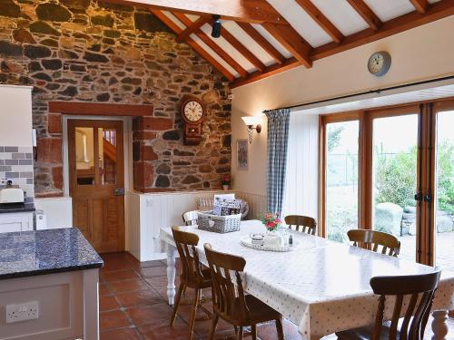 a kitchen with a table with chairs and a stone wall at The Wee Byre in Shawhead
