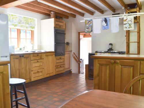 a large kitchen with wooden cabinets and a table at Cae Ocyn in Dwyran