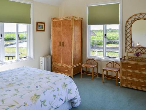 a bedroom with a bed and a dresser and windows at The Studio in Hickling