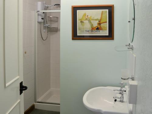 a bathroom with a sink and a picture on the wall at The Studio in Hickling