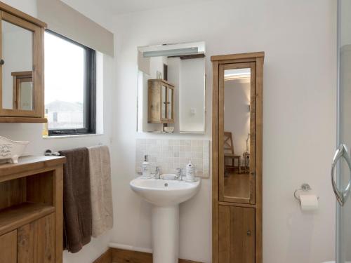 a white bathroom with a sink and a mirror at Summer House Stables in Catfield