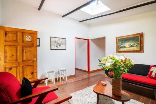 a living room with a red couch and a table at Cabaña de Hacienda Nebraska in Zipacón