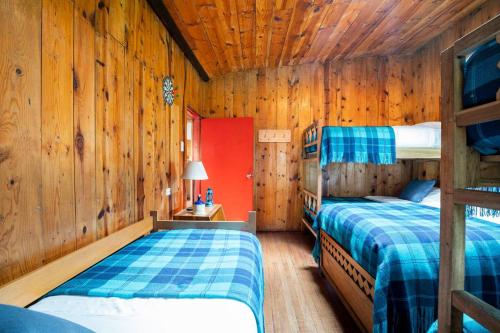 two beds in a room with wooden walls at Cabaña de Hacienda Nebraska in Zipacón