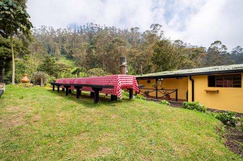 a picnic table in a field next to a house at Cabaña de Hacienda Nebraska in Zipacón