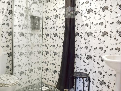a bathroom with a shower with a black and white wallpaper at The Writing Room in Barford