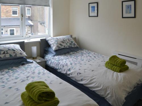 a bedroom with two beds with green towels on them at Kittiwakes in Amble