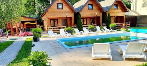 a house with a swimming pool with chairs and a house at Ośrodek 9Amber in Pobierowo