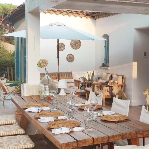 - une table en bois avec des verres et des serviettes sur la terrasse dans l'établissement Domaine l'Oiseau Bleu, à Sainte-Maxime