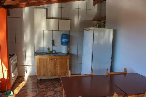 a kitchen with a refrigerator and a wooden table at Pousada entre Paraísos in Angra dos Reis