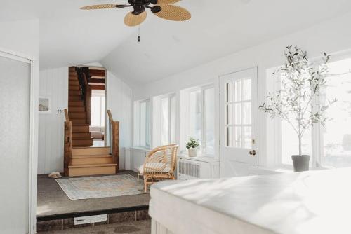 een witte woonkamer met een plafondventilator bij Beach House in Niagara in Wainfleet