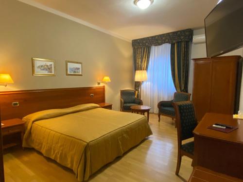 Habitación de hotel con cama, escritorio y sillas en Hotel Il Vigneto, en Gattinara