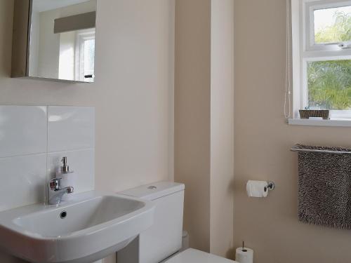 a white bathroom with a sink and a mirror at Corney Grain in Teversham