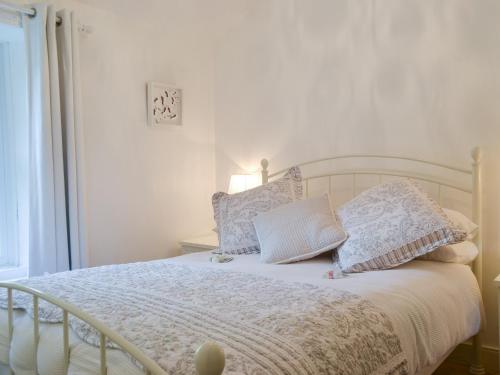 een slaapkamer met een wit bed met kussens erop bij Fairholme in Braithwaite