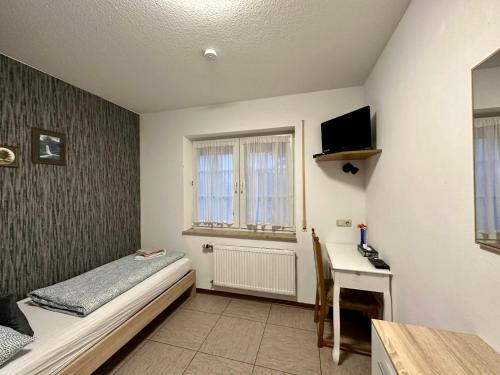een slaapkamer met een bed en een bureau met een televisie bij Hotel Landhaus Köln in Lindlar
